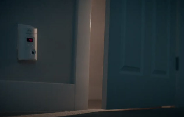 A carbon monoxide detector by a door.